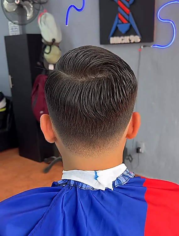 Después: corte clásico con raya al lado y degradado bajo, visto desde atrás frente al letrero de Black 98
